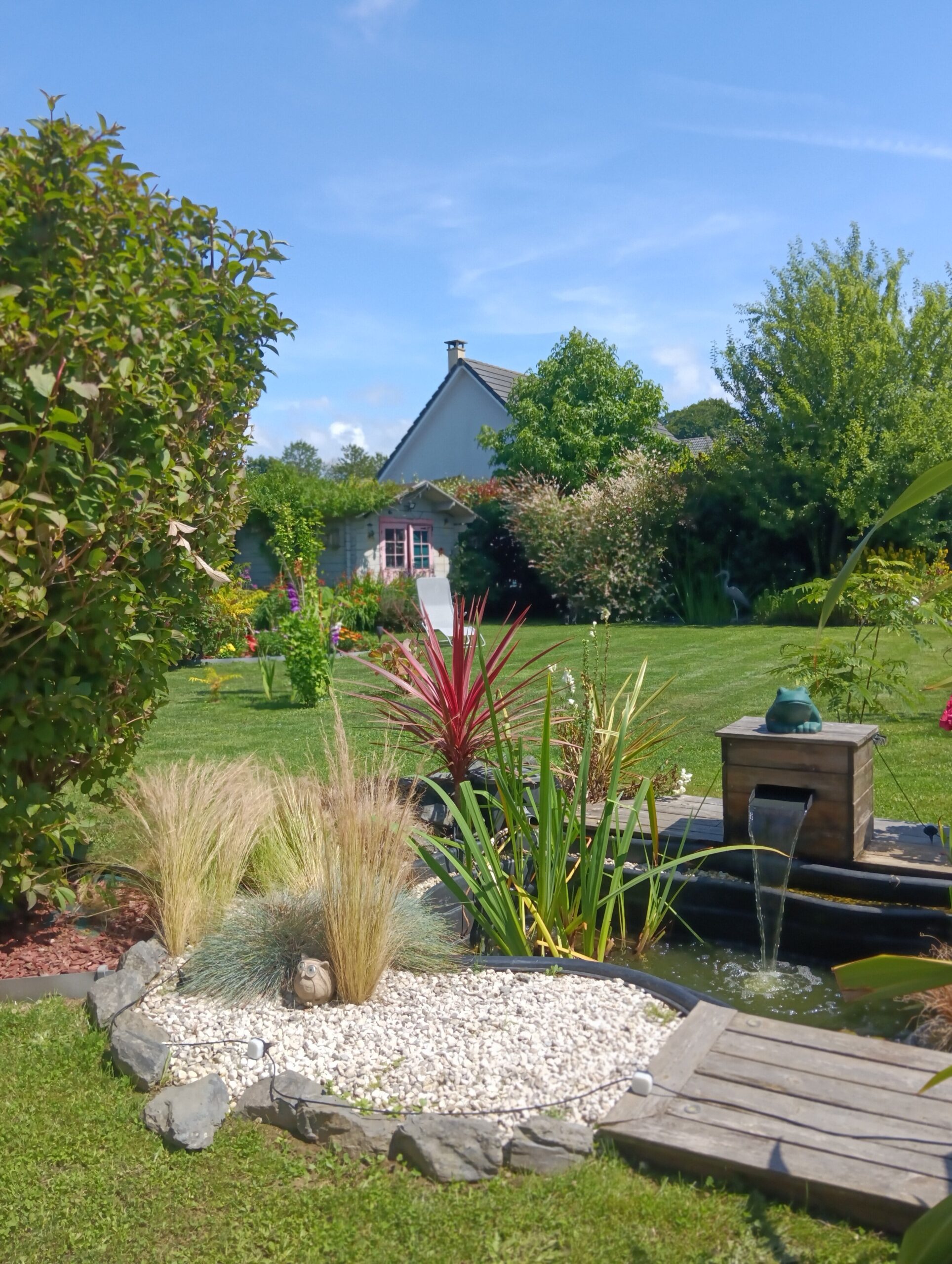 bassin d 'eau douce contenant des poissons et sa fontaine dans un jardin aménagé en normandie